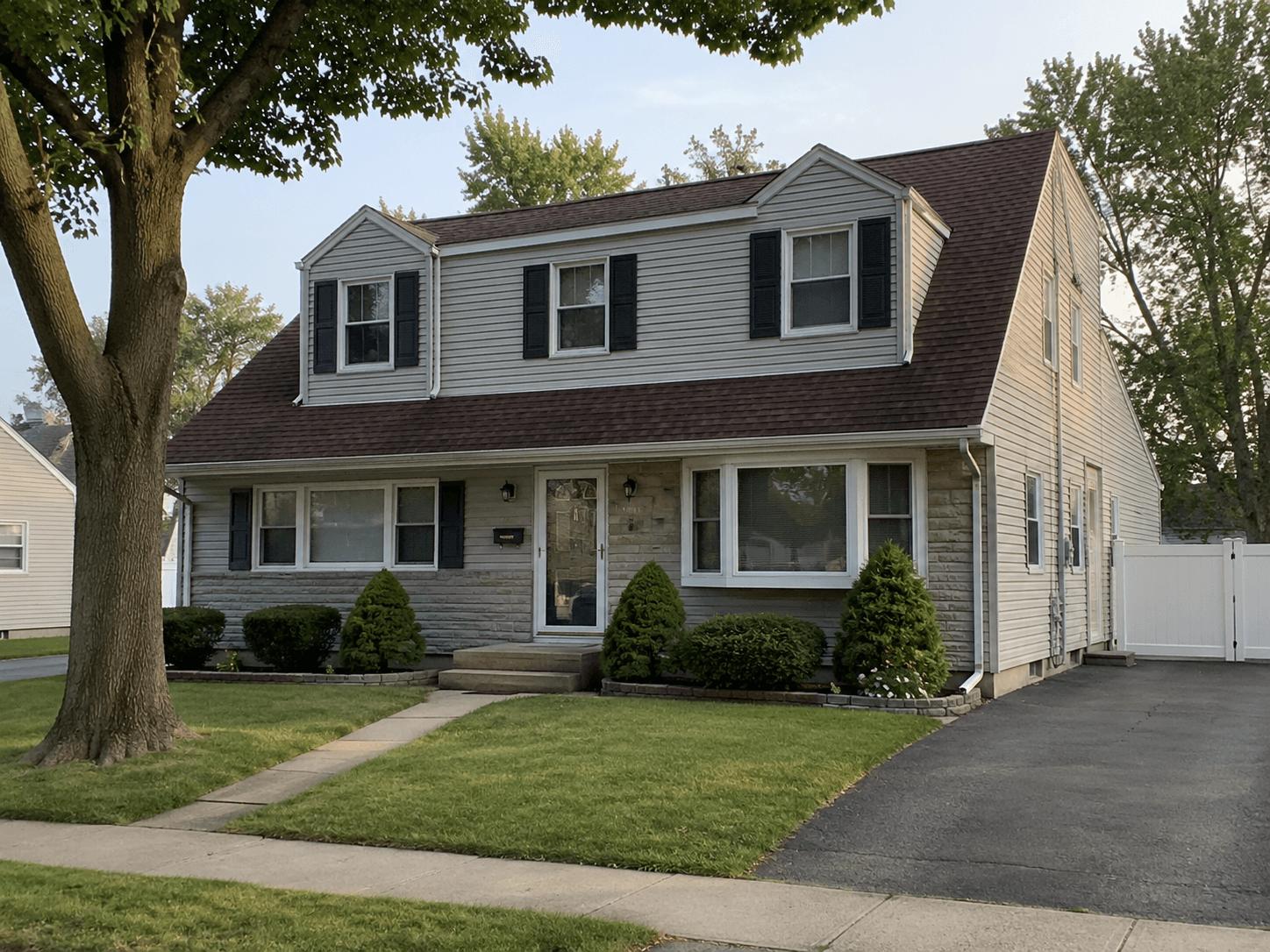 A sunlit residential street of well-kept single-family homes